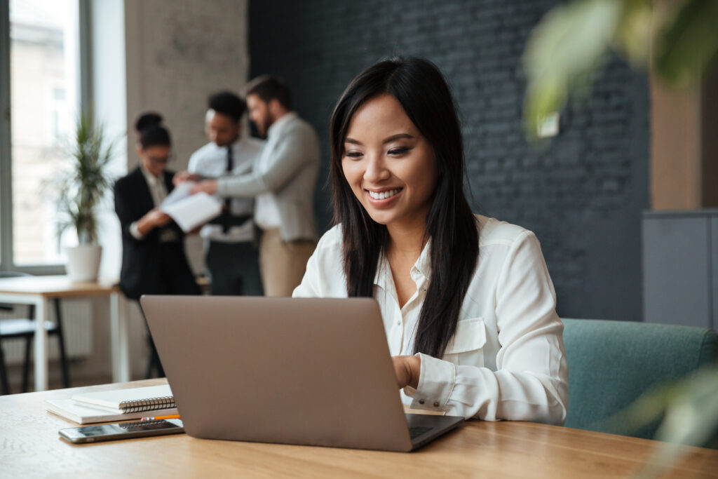 Cheerful Young Asian Business Woman Using Laptop - PAVON | Contabilidade em São Paulo