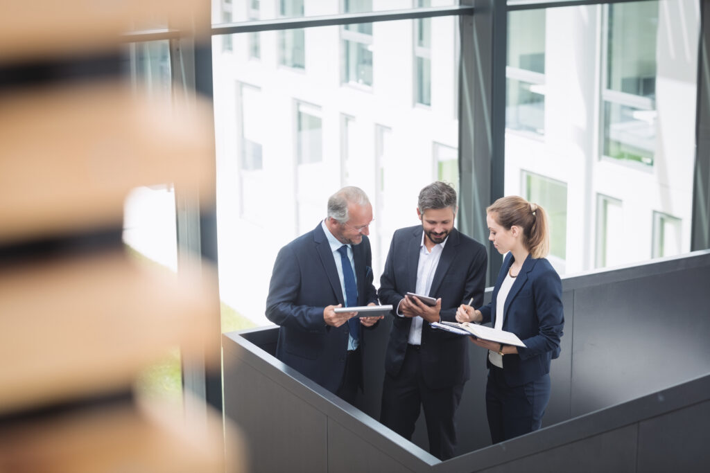 Group Of Businesspeople Having A Discussion Near Staircase In Office - PAVON | Contabilidade em São Paulo