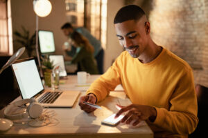 Happy Black Businessman M Banking While Working Late In The Offi - PAVON | Contabilidade em São Paulo