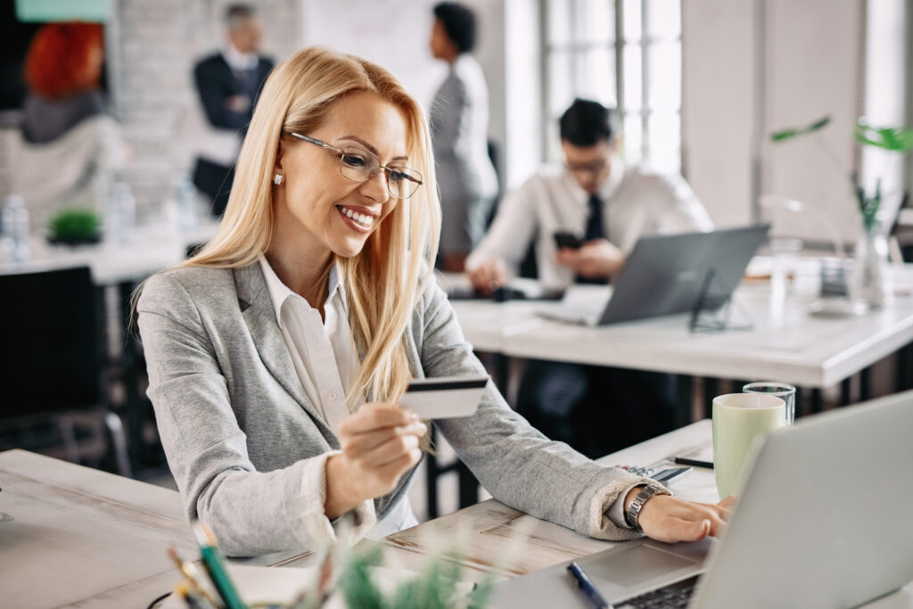 Happy Businesswoman Holding Credit Card While Using Laptop For O - PAVON | Contabilidade em São Paulo