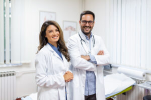 Portrait Of Smiling Young Doctors Standing Together. Portrait Of Medical Staff Inside Modern Hospital Smiling To Camera - PAVON | Contabilidade em São Paulo