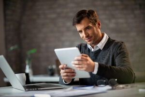 Happy Businessman Working On Touchpad While Being In The Office. - PAVON | Contabilidade em São Paulo