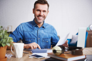 Portrait Of Smiling Man Calculating His Monthly Expenses - PAVON | Contabilidade em São Paulo