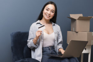 Smiley Woman Posing With Credit Card Laptop Boxes - PAVON | Contabilidade em São Paulo