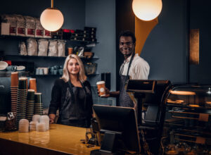 Couple Barista Standing Behind A Counter In The Coffee Shop. - PAVON | Contabilidade em São Paulo