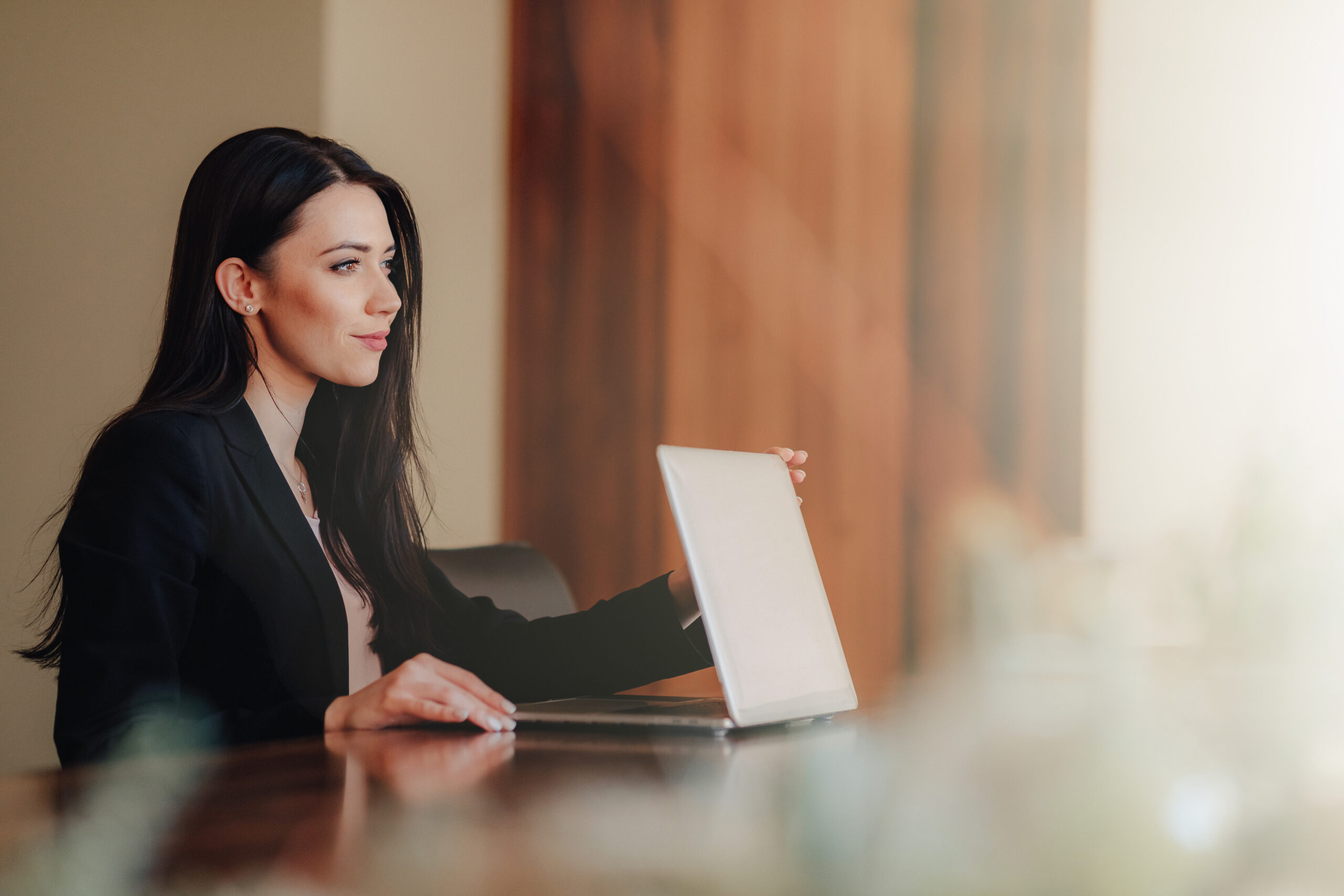 Young Attractive Emotional Girl In Business Style Clothes Sitting At A Desk On A Laptop And Phone In The Office Or Auditorium - PAVON | Contabilidade em São Paulo