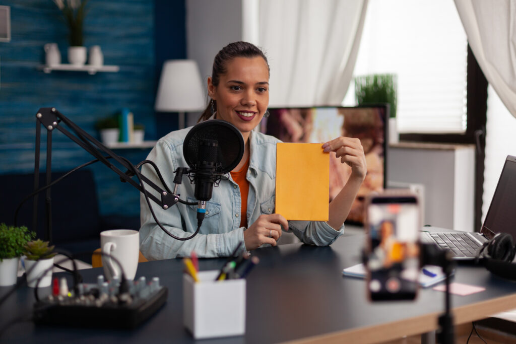 Woman Influencer Presenting Yellow Product Box In Front Of Recording Smartphone. - PAVON | Contabilidade em São Paulo